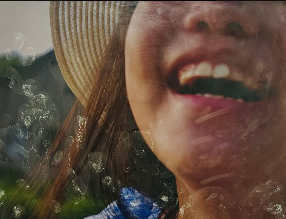 AP Photography: a laughing face under a sun hat, layered with texture